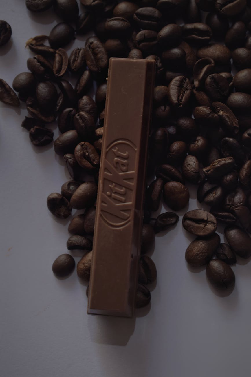 A single chocolate bar amidst scattered coffee beans for a rich, aromatic composition.