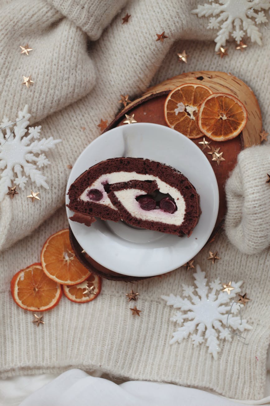 Slice of chocolate cake with dried oranges and snowflakes on cozy sweater, ideal for winter holidays.