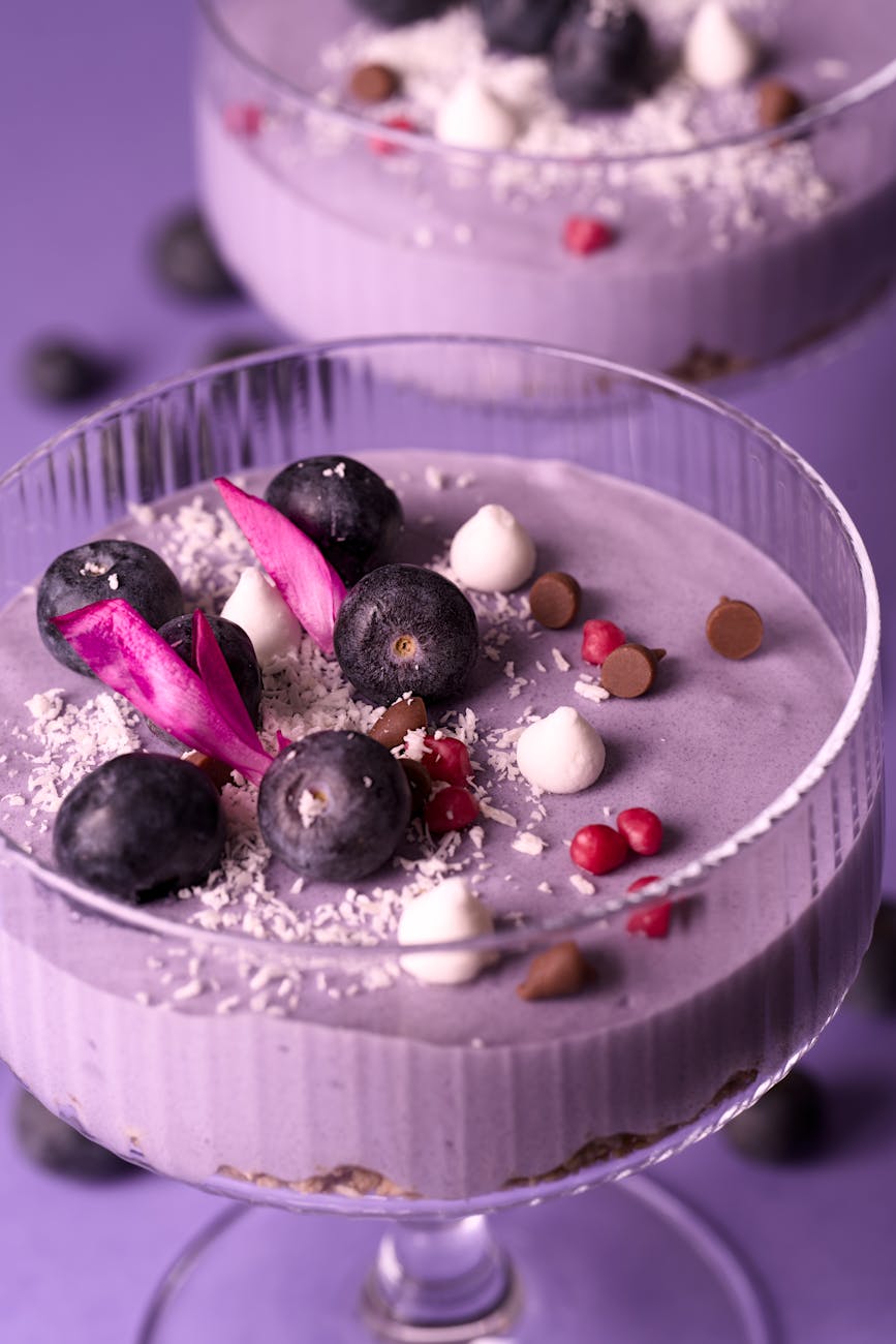 Vibrant blueberry parfait topped with coconut flakes, chocolate chips, and decorative flowers.