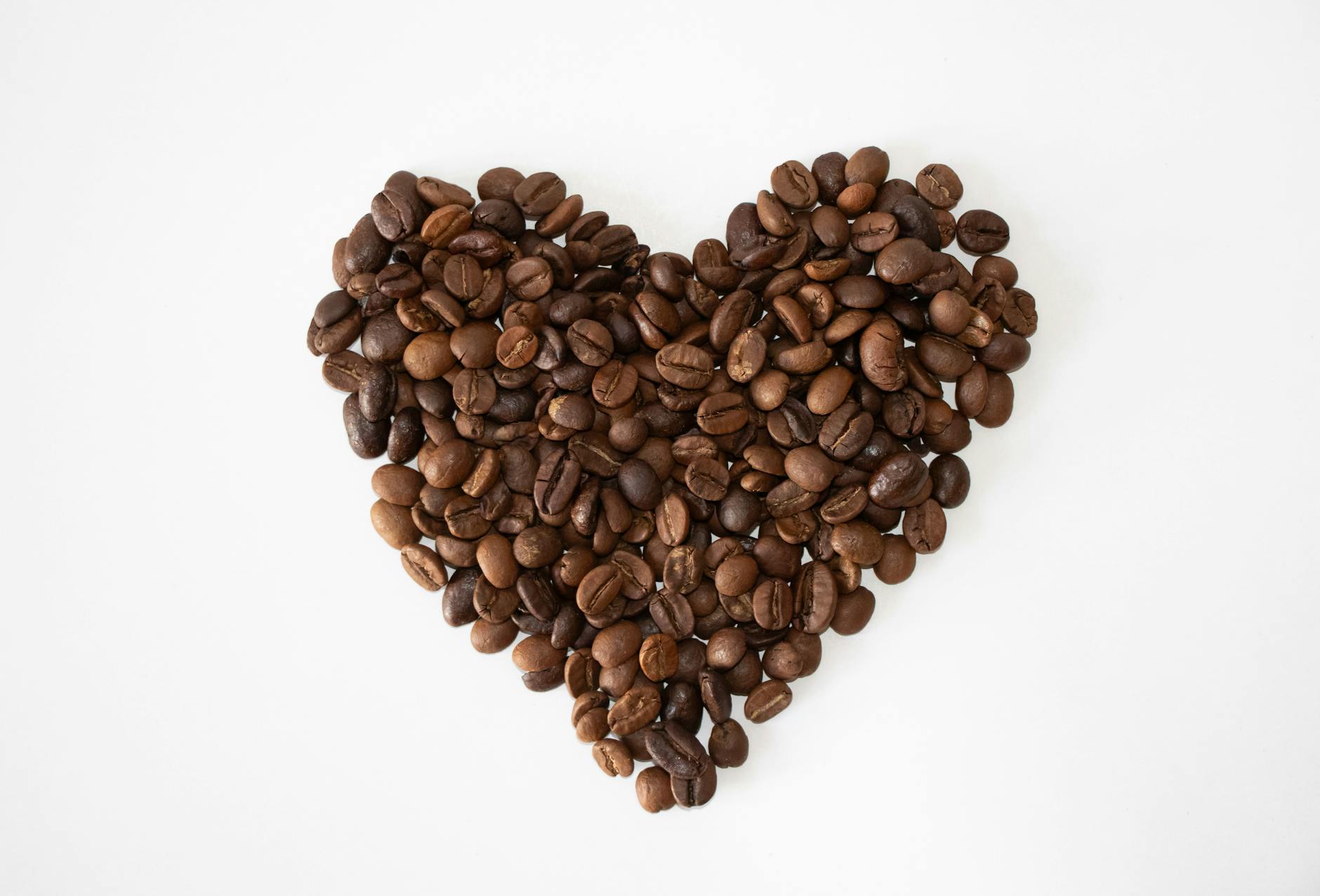 Artistic arrangement of coffee beans forming a heart shape on a clean white background.